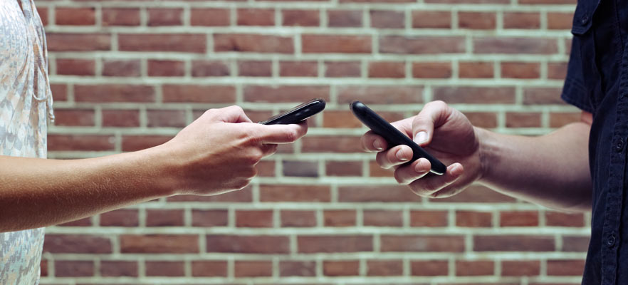 Two people exchanging contact information on their cell phones.